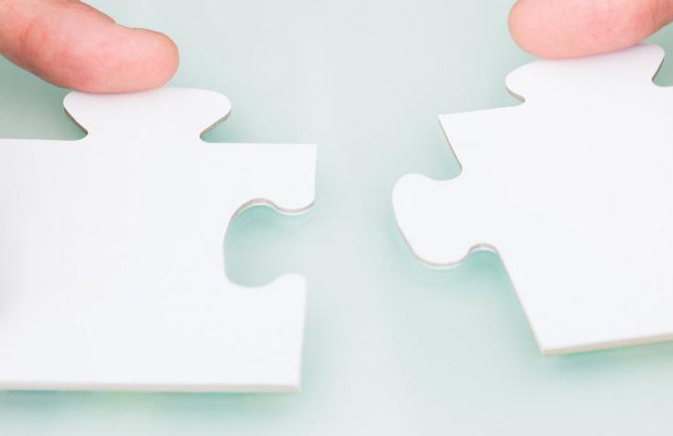 Hands holding two white puzzle pieces