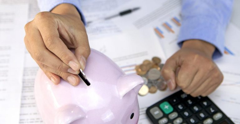 Person putting coins into a piggy bank