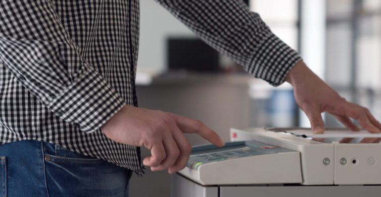 Man using multifunction printer machine in office setting