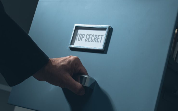 Man pulling out drawer on filing cabinet that says top secret